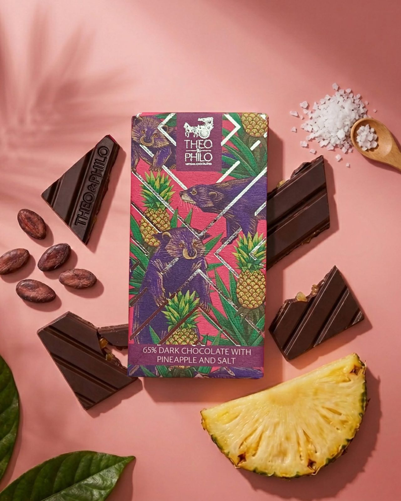 Theo & Philo chocolate bar with dark chocolate pieces, cacao beans, and a pineapple wedge