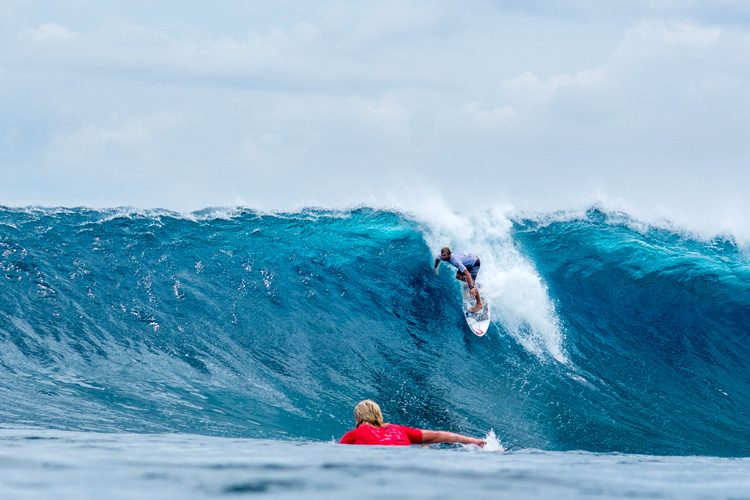 Surfer riding a large blue wave in Siargao